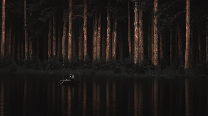 Person in a boat on a lake with a forest background