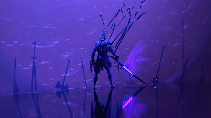 Warrior with glowing sword surrounded by weapons