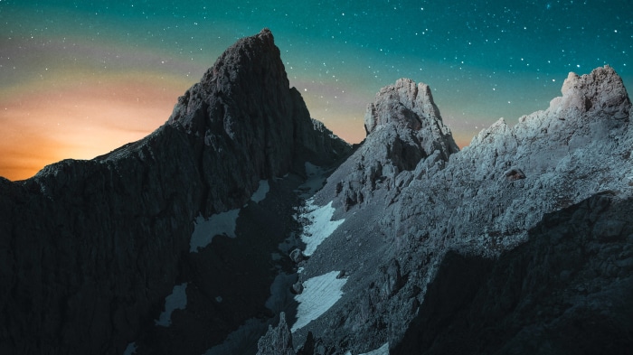 Mountains under a starry sky with orange glow