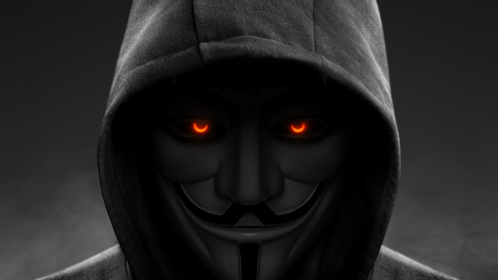 Anonymous figure in a hoodie with glowing eyes