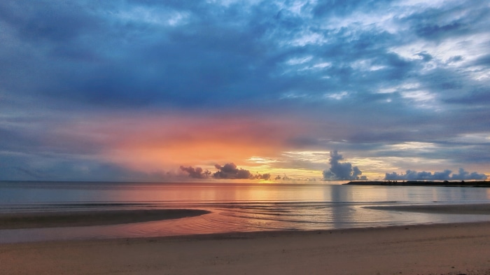 Sunrise over a calm beach with colorful clouds