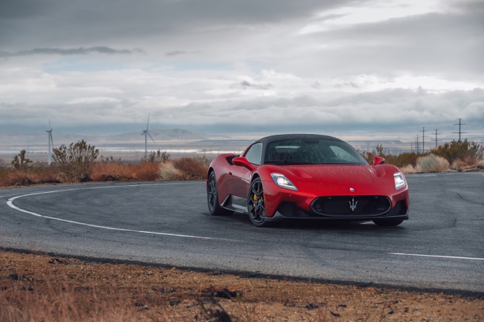Red Maserati MC20 on a winding road with wind turbines