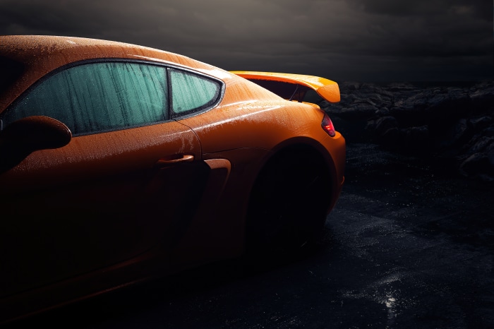 Orange Porsche Cayman covered in water droplets