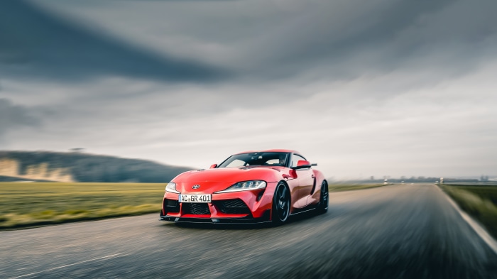 Red Toyota Supra GR 401 driving on a road