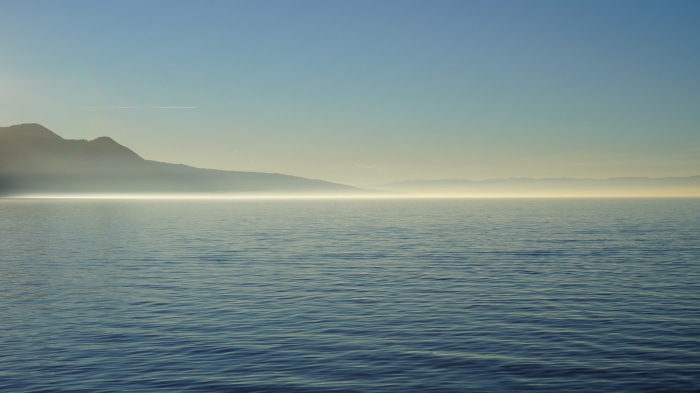 Lake and mountains shrouded in fog at sunrise