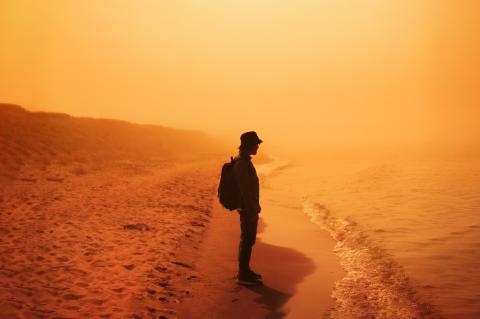 Man with backpack on a foggy beach
