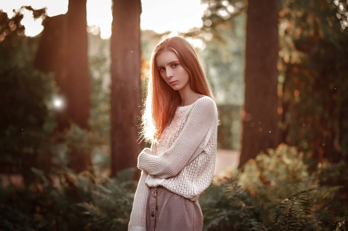 Redhead model in a white sweater and skirt in forest