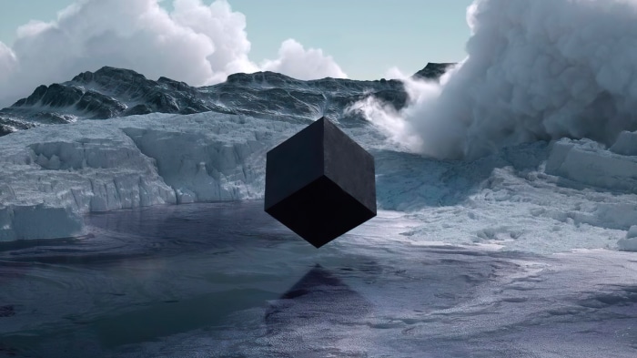Black cube floating over icy water with mountains