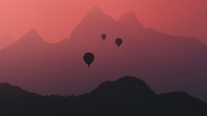 Hot air balloons over mountains at sunset