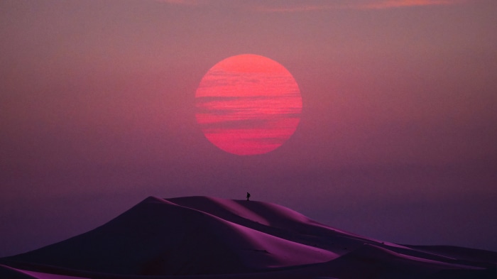 Person standing on sand dunes at sunset 4K