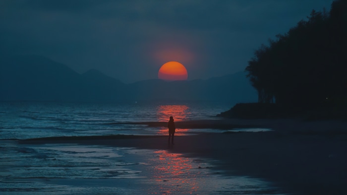 Person on beach watching sunset over ocean