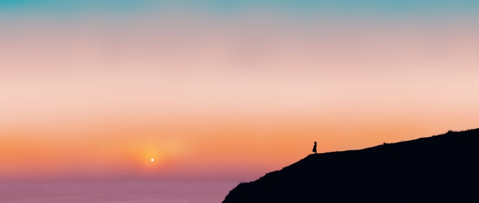 Silhouette of a person on a cliff at sunset