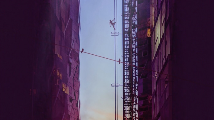Man climbing on a wire between buildings