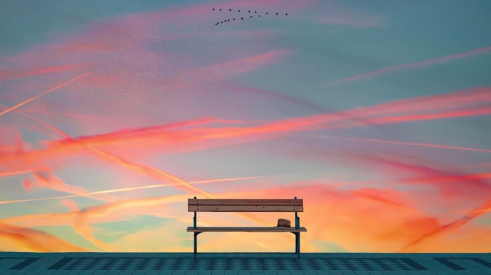 Bench with hat against colorful sky