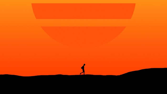 Silhouette of a person walking against a large orange sun