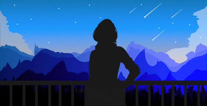 Silhouette of a person watching shooting stars over mountains