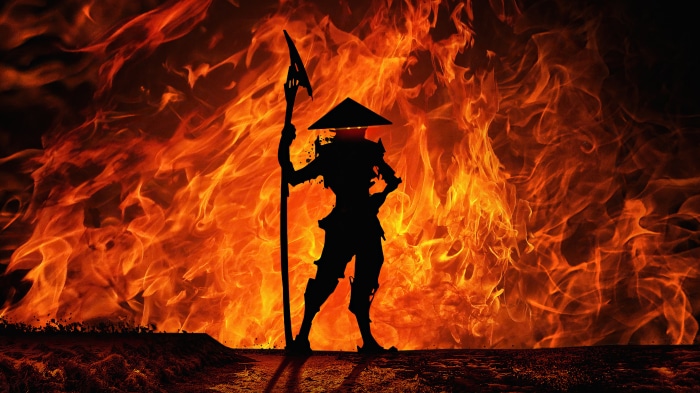 Silhouette of a warrior with a spear against a fiery background