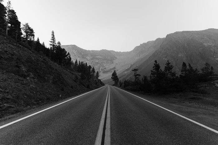 Monochrome road through a mountain landscape with trees