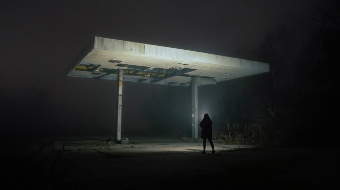 Person with flashlight at abandoned gas station