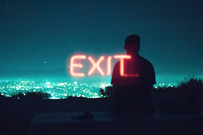 Silhouette with neon EXIT sign over city lights