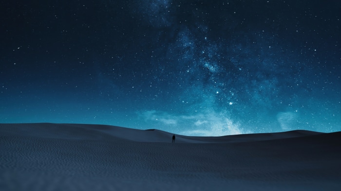 Man standing in desert under starry sky