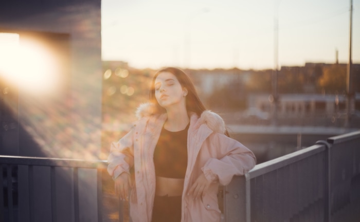 Girl in pink jacket on bridge at sunset