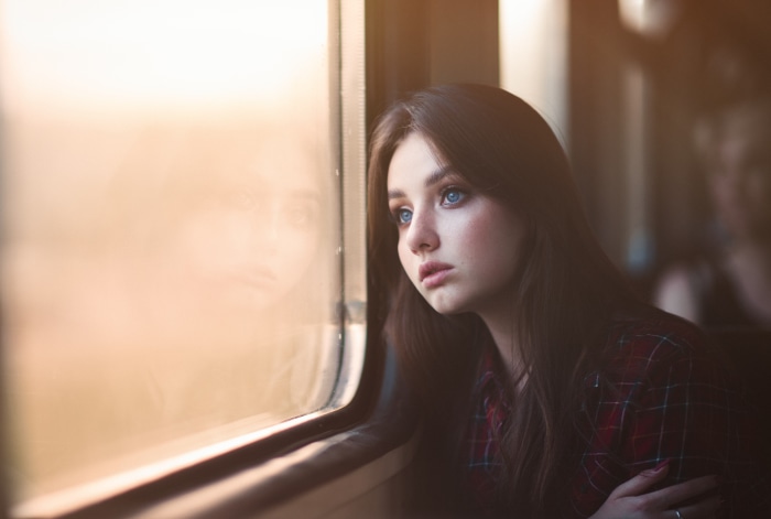 Girl with blue eyes looking out train window