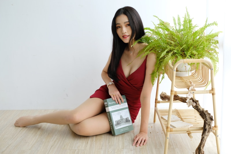 Asian woman in red dress holding a book