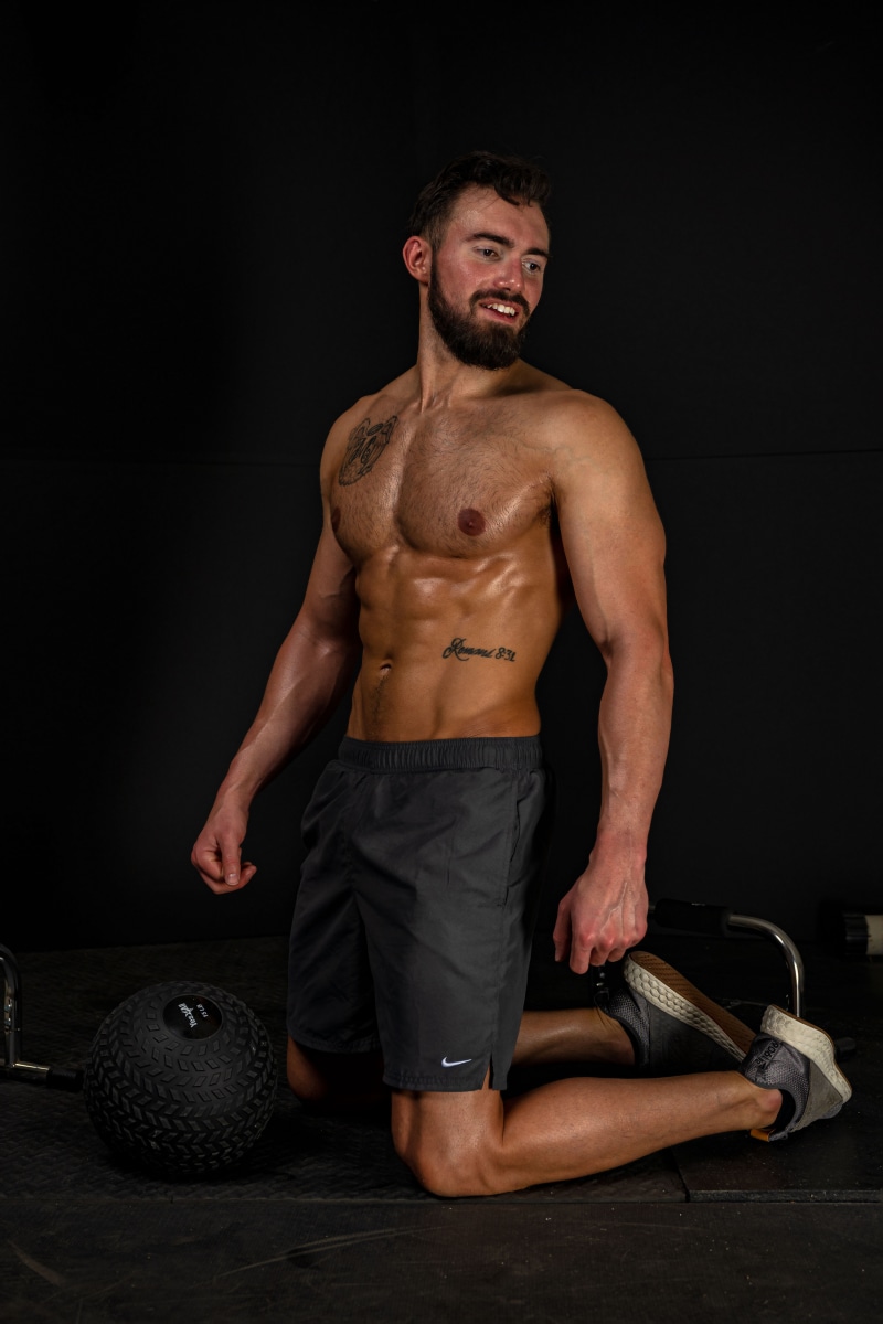 Man with muscular physique kneeling in gym