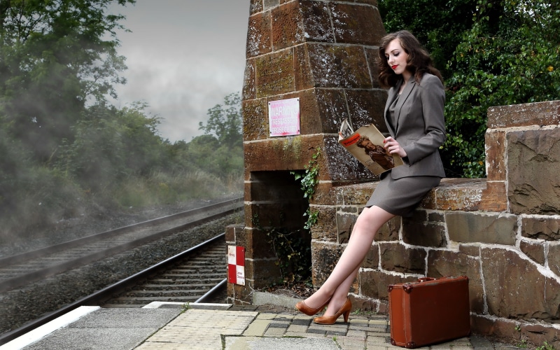 Woman in suit reading magazine at train station