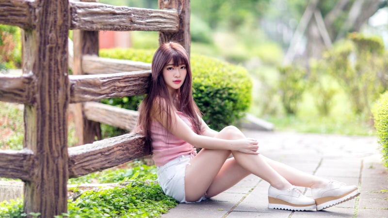 Asian woman with brown hair in pink top and white shorts