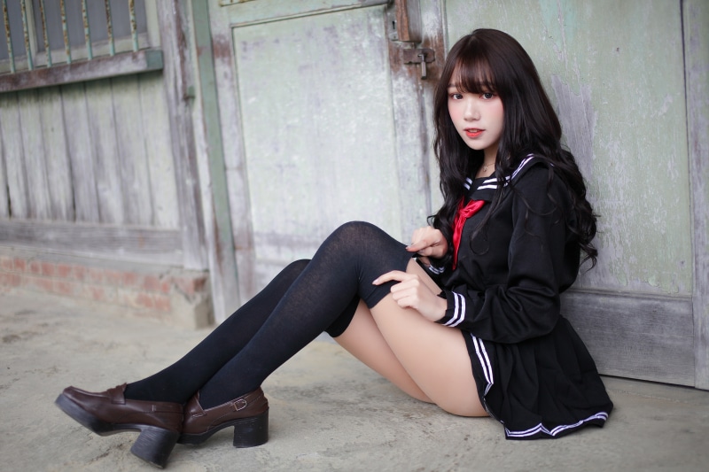 Asian schoolgirl in uniform sitting outdoors