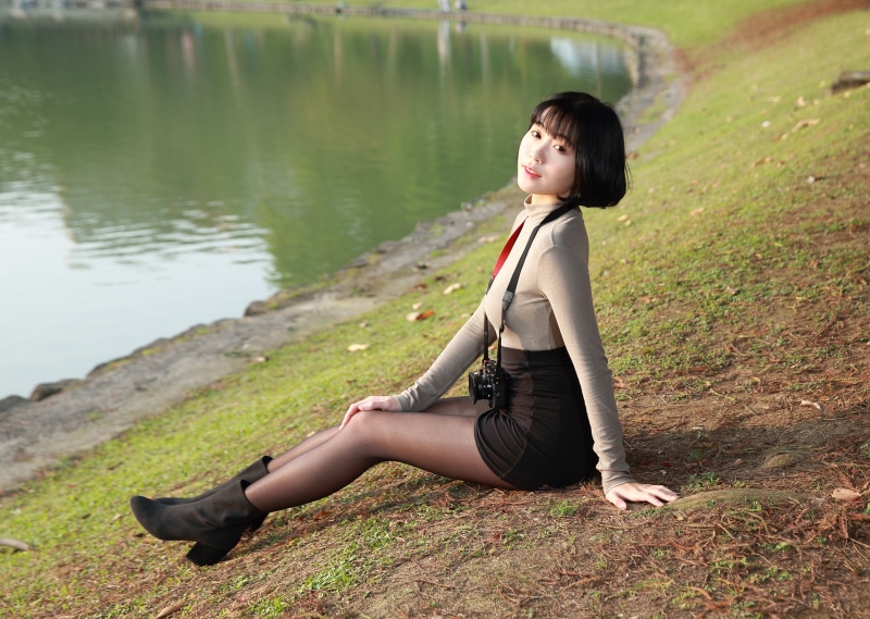 Asian girl with camera sitting by a lake
