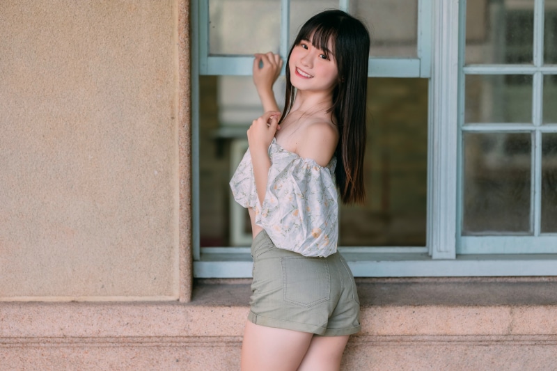 Asian girl in shorts and blouse posing by window
