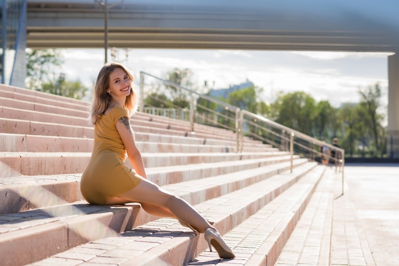 Blonde girl in yellow dress sitting on stairs