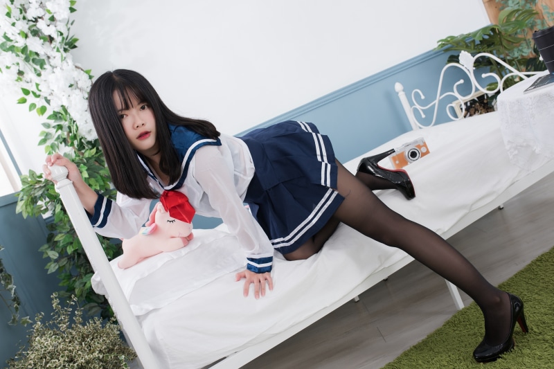 Brunette girl in school uniform posing on a bed