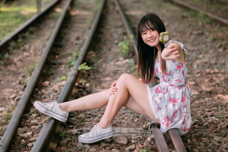 Asian girl sitting on train tracks