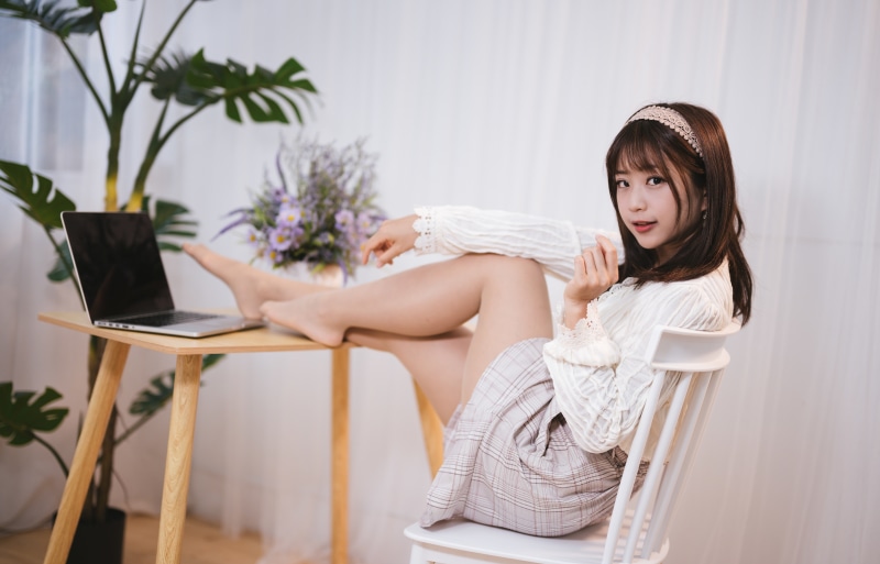 Asian woman with brown hair sitting by a table with a laptop