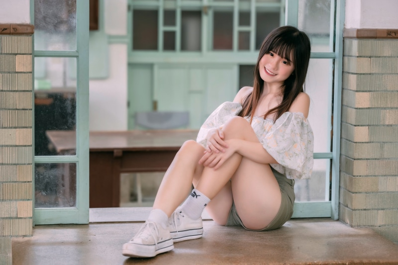 Asian woman smiling, sitting by a window