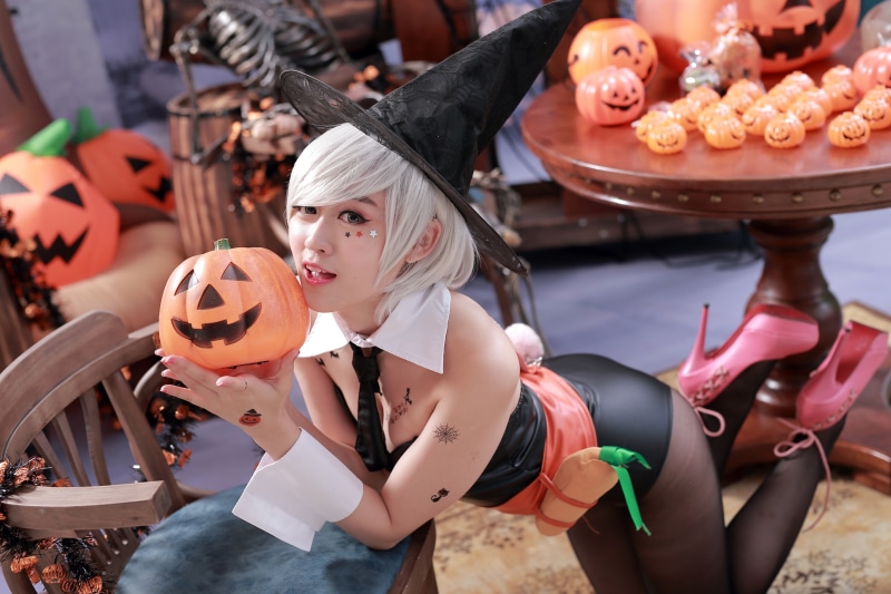 Asian woman in witch costume holding a pumpkin