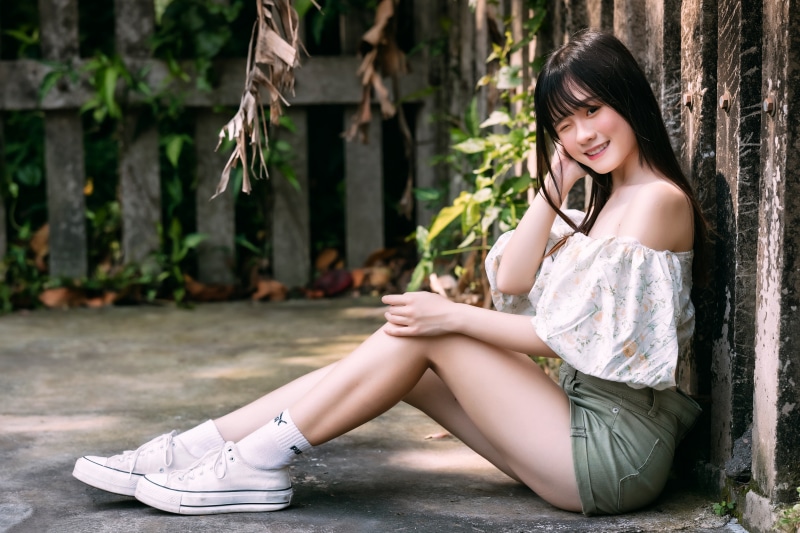 Asian girl sitting by a wall