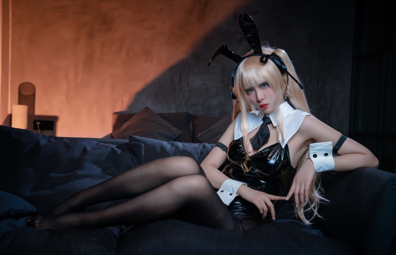 Blonde girl in bunny ears cosplay sitting on couch