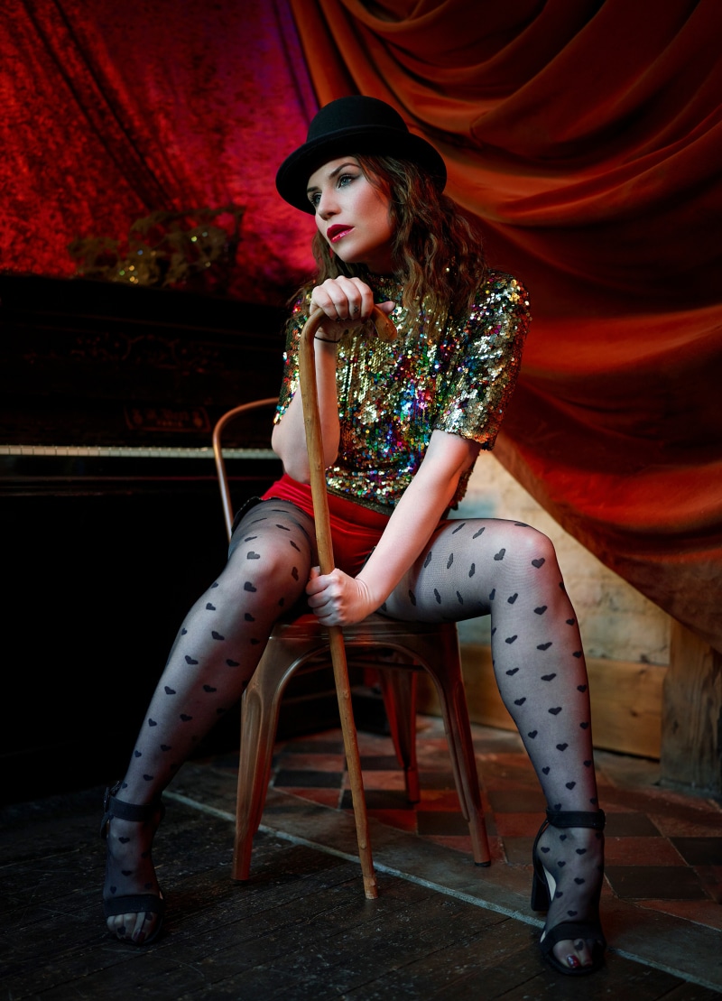 Woman in sequined top and heart patterned tights holding cane