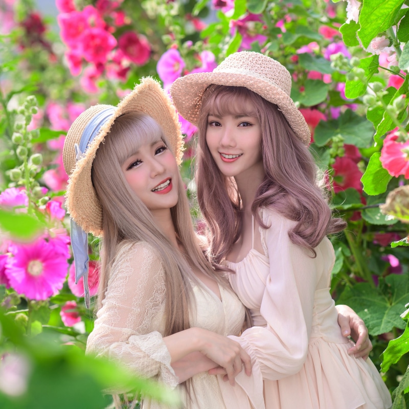 Two Asian women in hats and dresses smiling