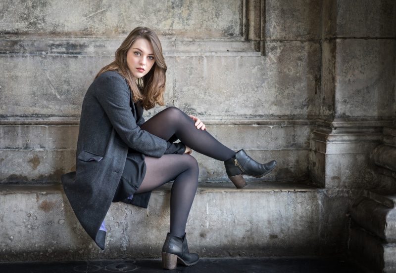 Woman in coat and pantyhose sitting on stone steps