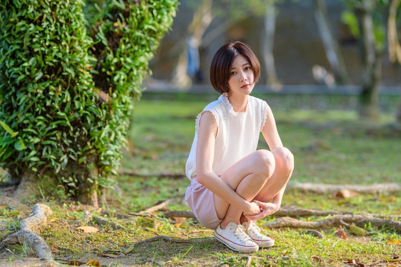 Asian woman crouching in a park