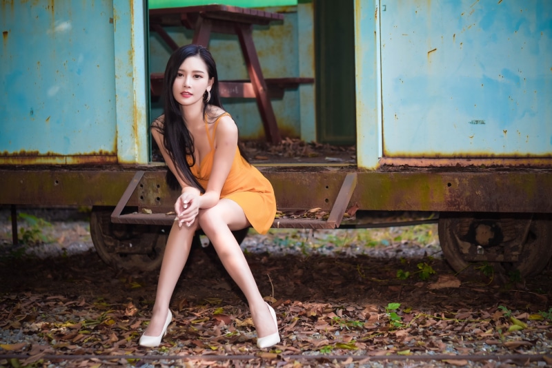 Asian woman in orange dress sitting on train car