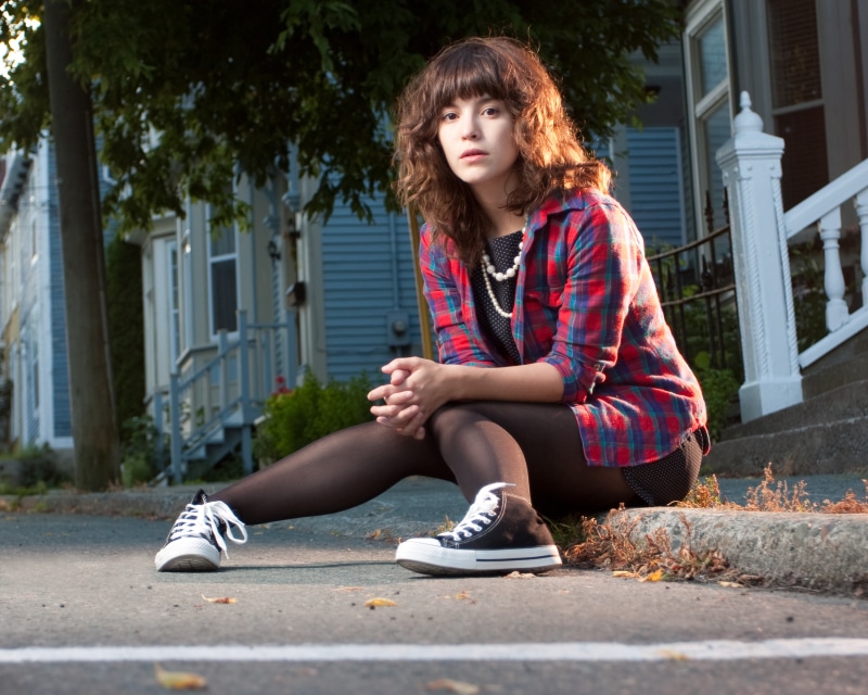 Woman in plaid shirt sitting on curb