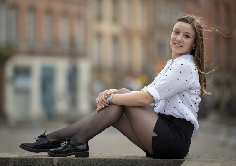 Woman in polka dot shirt and black skirt sitting