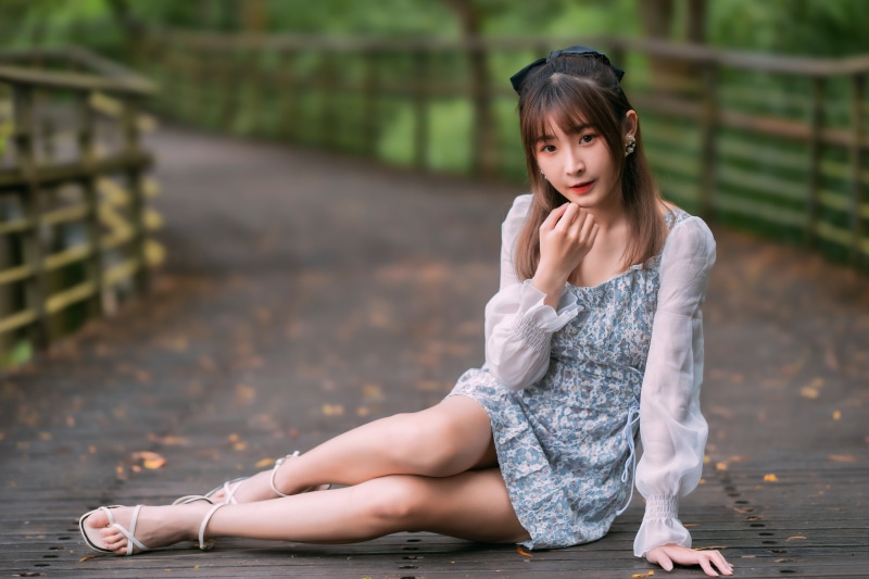 Asian woman in dress sitting on a wooden bridge